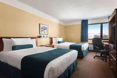a hotel room with two beds and a desk and a window at Hotel Days Inn Blainville & Centre de Conférence in Blainville