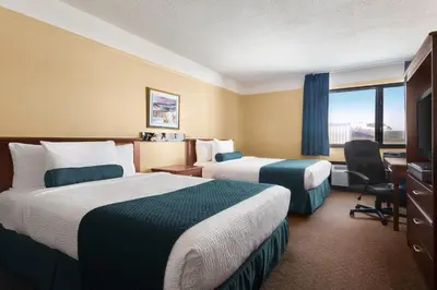 a hotel room with two beds and a desk and a window at Hotel Days Inn Blainville & Centre de Conférence in Blainville