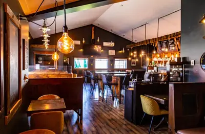 a restaurant with a bar and tables and chairs at Hotels Hébert in Bécancour