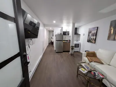 a living room with a white couch and a kitchen at Motel LA RÉFÉRENCE in Trois-Rivières