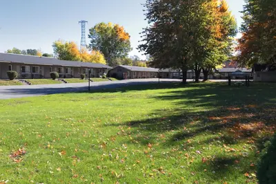 a park with trees and a building in the background at Le Deauville Motel in Trois-Rivières