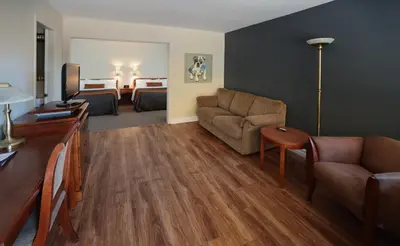 a living room with a couch and a room with two beds at Le Deauville Motel in Trois-Rivières