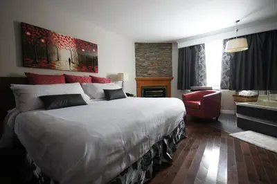a bedroom with a large bed and a red chair at Le Deauville Motel in Trois-Rivières