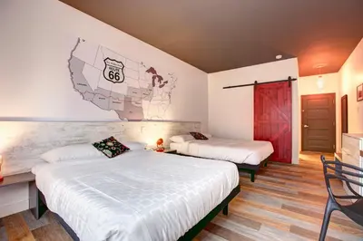 a bedroom with two beds and a wall with a mural at Hotel Historique et Manoir Route 66 in Saint-Victor