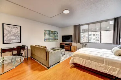 a bedroom with a bed and a couch and a tv at LaCité Cozy Apartment Close to Central Montreal in Montréal