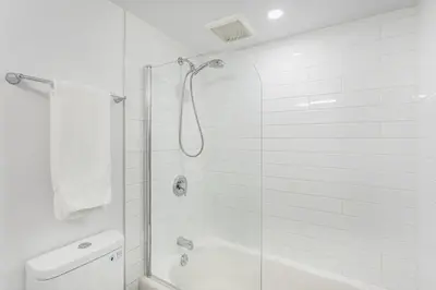 a white bathroom with a shower and a toilet at LaCité Cozy Apartment Close to Central Montreal in Montréal