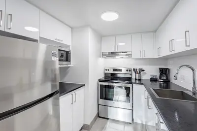 a kitchen with white cabinets and stainless steel appliances at LaCité Cozy Apartment Close to Central Montreal in Montréal