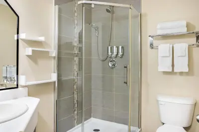 a bathroom with a shower with a toilet and a sink at Days Inn by Wyndham Berthierville in Berthierville