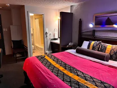 a hotel room with a large bed with a red blanket at Hotel L'Express in Longueuil