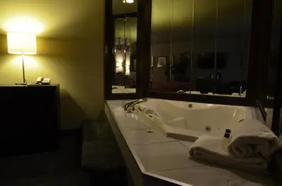 a bathroom with a tub and a large mirror at Hotel L'Express in Longueuil