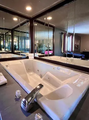 a large white bath tub in a bathroom at Hotel L'Express in Longueuil