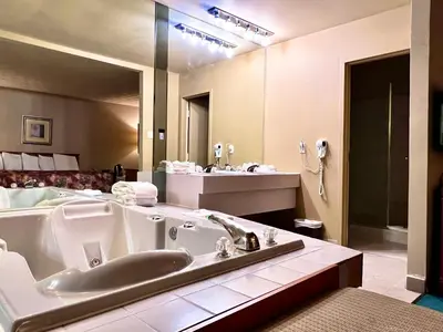 a large bathroom with a tub and a bed at Hotel L'Express in Longueuil