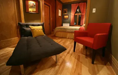 a bedroom with a couch and a red chair at A La Carte Bed & Breakfast in Montréal