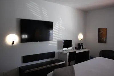 a hotel room with a desk and a television on the wall at Le Dauphin St-Hyacinthe in Saint-Hyacinthe