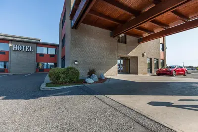 a building with a car parked in a parking lot at Le Dauphin St-Hyacinthe in Saint-Hyacinthe
