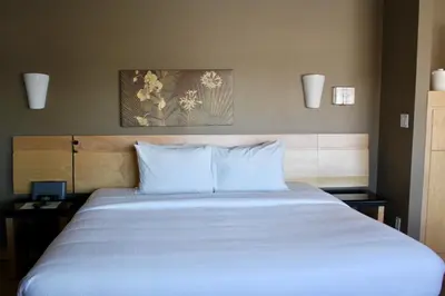 a bedroom with a large white bed with two night stands at Le Dauphin St-Hyacinthe in Saint-Hyacinthe