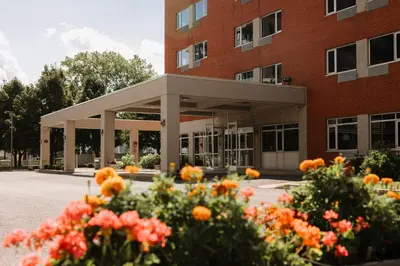 a building with flowers in front of it at Le Dauphin Montréal-Longueuil in Longueuil