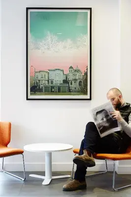 a man sitting on a chair reading a magazine at Le Dauphin Montréal-Longueuil in Longueuil