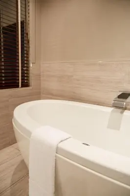 a white bath tub in a bathroom with a towel on it at Le Dauphin Montréal-Longueuil in Longueuil
