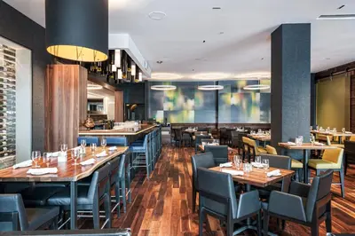 a restaurant with wooden tables and blue chairs at Hotel Bonaventure Montreal in Montréal