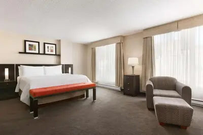a hotel room with a bed and a chair at Embassy Suites by Hilton - Montreal in Montréal