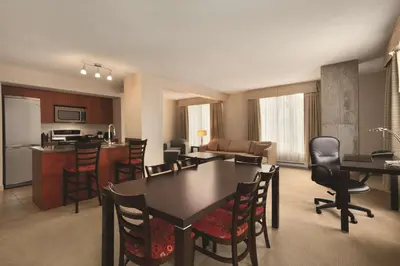 a kitchen and living room with a table and chairs at Embassy Suites by Hilton - Montreal in Montréal