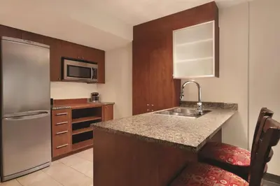 a kitchen with a sink and a stainless steel refrigerator at Embassy Suites by Hilton - Montreal in Montréal