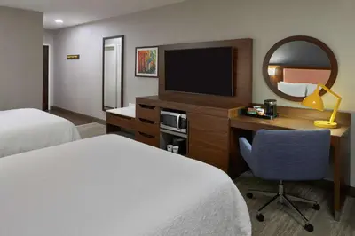 a hotel room with two beds and a desk with a television at Hampton Inn & Suites Montreal-Dorval in Dorval