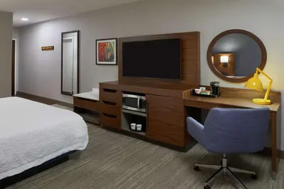 a hotel room with a bed and a desk with a television at Hampton Inn & Suites Montreal-Dorval in Dorval
