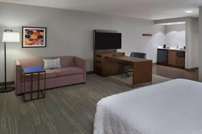 a hotel room with a couch and a desk with a television at Hampton Inn & Suites Montreal-Dorval in Dorval