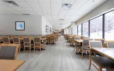 an empty room with tables and chairs and windows at L'Appartement Hôtel in Montréal