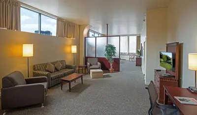 a living room with couches and chairs and a tv at Le Square Phillips Hôtel & Suites in Montréal