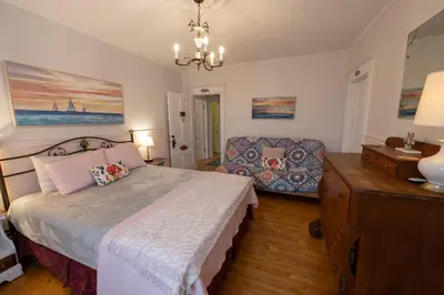 a bedroom with a bed and a couch and a chandelier at À Tout Venant B&B in Magog-Orford