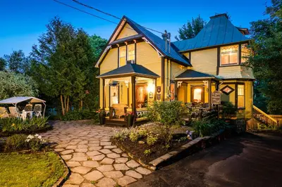 a yellow house with a porch and a patio at Les Matins de Victoria in Waterloo