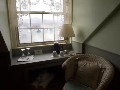 a desk with a lamp and a chair in front of a window at Au Manoir de la rue Merry in Magog-Orford