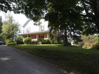 a white house with a tree and a driveway at Au Manoir de la rue Merry in Magog-Orford