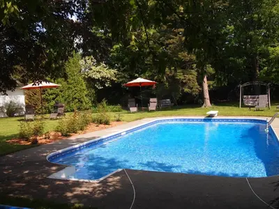 a swimming pool in a yard with an umbrella at Au Manoir de la rue Merry in Magog-Orford