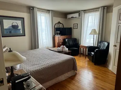 a hotel room with a bed and two chairs at Au Manoir de la rue Merry in Magog-Orford