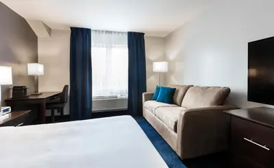 a hotel room with a couch and a tv at Imperia Hotel & Suites Saint-Eustache in Saint-Eustache