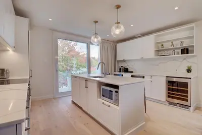a kitchen with white cabinets and a large window at Ripplecove Hotel & Spa in Ayer's Cliff