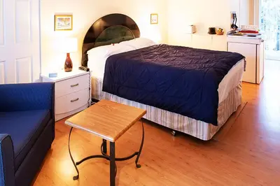 a bedroom with a bed and a table and a couch at Chalet Beaconsfield Motel in Beaconsfield