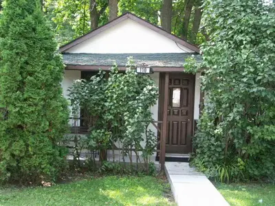 a small house with a brown door in a yard at Chalet Beaconsfield Motel in Beaconsfield
