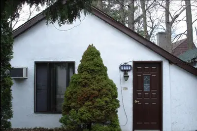 a white house with a door and a christmas tree at Chalet Beaconsfield Motel in Beaconsfield