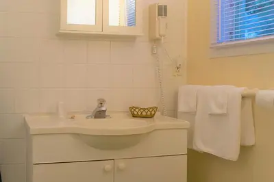a white bathroom with a sink and towels at Chalet Beaconsfield Motel in Beaconsfield