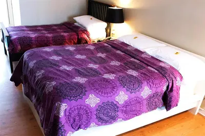 two beds in a room with a purple comforter at Chalet Beaconsfield Motel in Beaconsfield