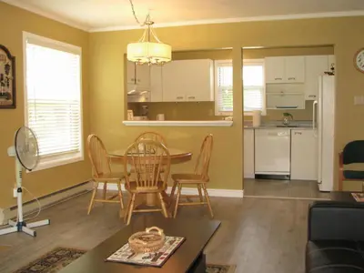 a living room with a table and chairs and a kitchen at Arkadia Condo Magog in Magog-Orford