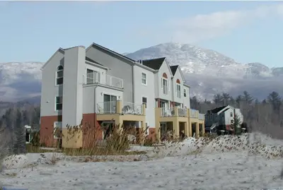 a house in the snow with a mountain in the background at Arkadia Condo Magog in Magog-Orford