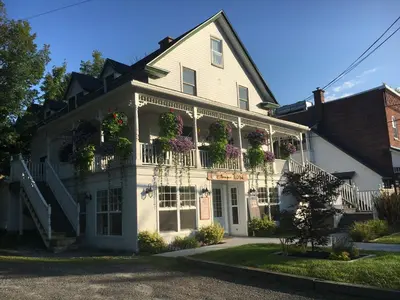 a white house with flowers on the balconies at Suites North Hatley in North Hatley