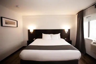 a bedroom with a large white bed with two lamps at Hotel Newstar Montréal in Montréal