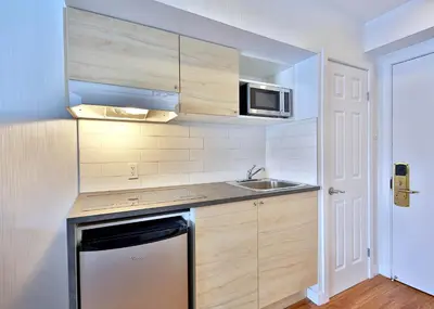a small kitchen with a sink and a microwave at Hotel Newstar Montréal in Montréal